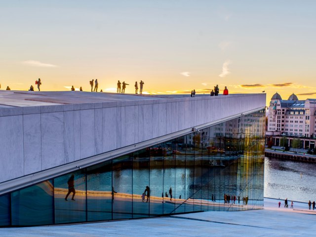 People standing on bridge over river in Oslo, Norway at sunset