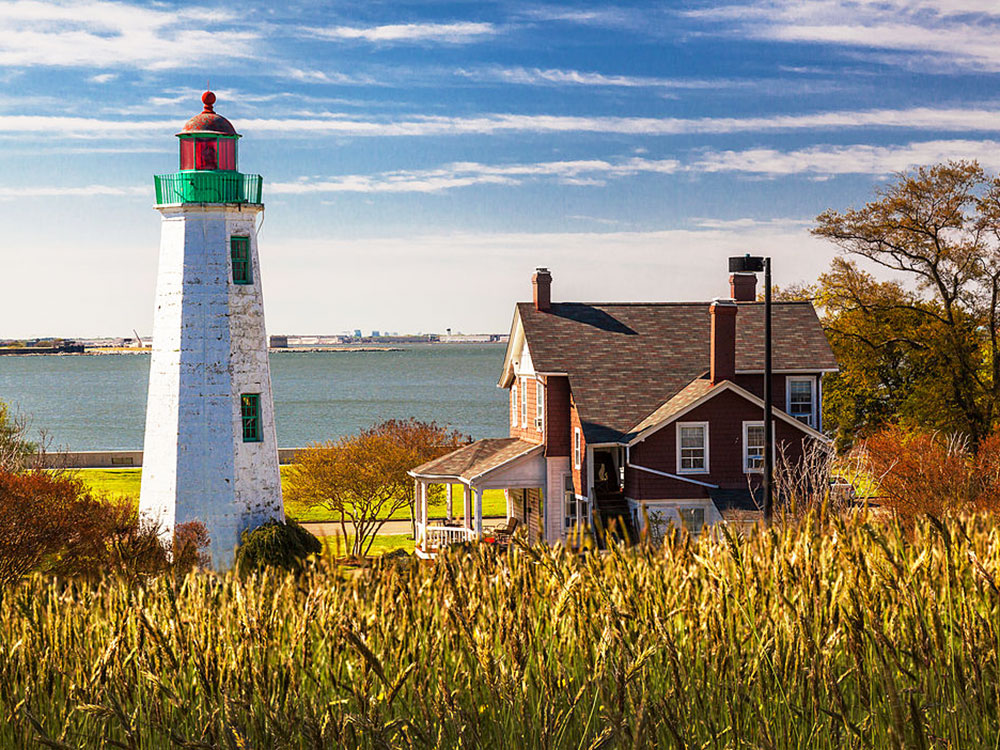 A white lighthouse next to a red-brick home