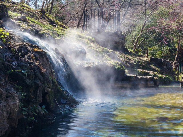 A picture of a waterfall cascading over moss-covered rocks into a pond