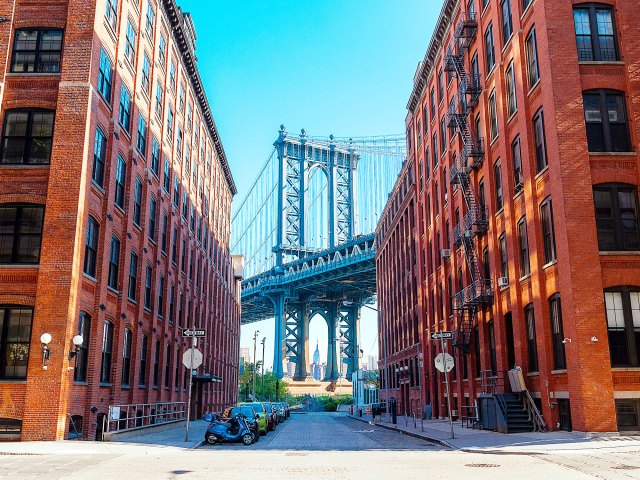 View of Williamsburg Bridge between brick buildings in Brooklyn