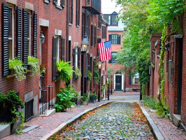 Narrow cobblestone lane between brick row homes in Boston, Massachusetts