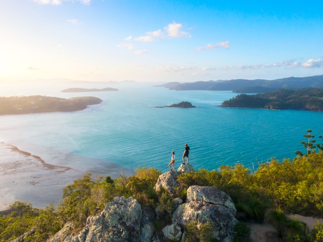Two hikers on rock overlooking bay