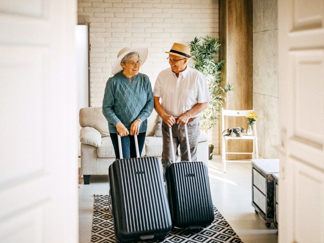 Older couple rolling suitcases into hotel room