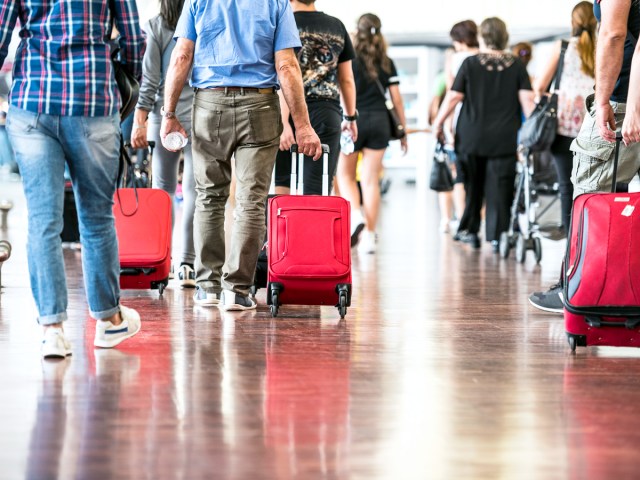 Airline passengers rolling suitcases through airport